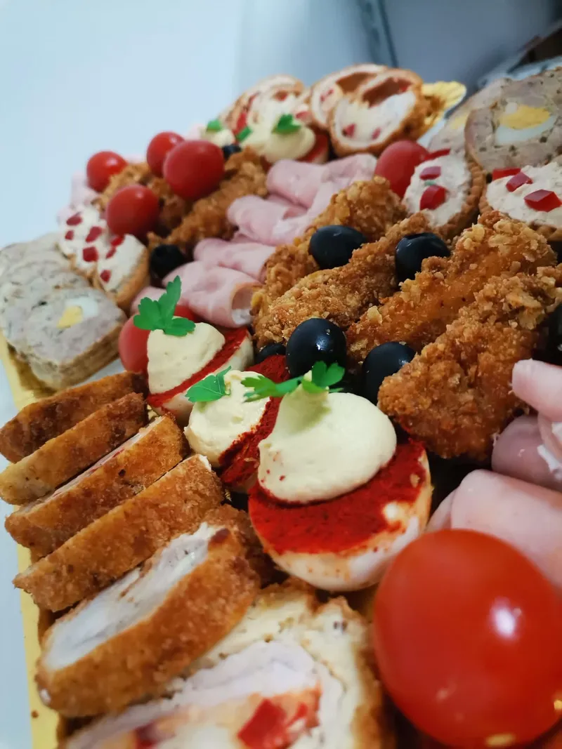 Prim-plan cu un platou de canapele: rulouri pane, roșii umplute și șuncă