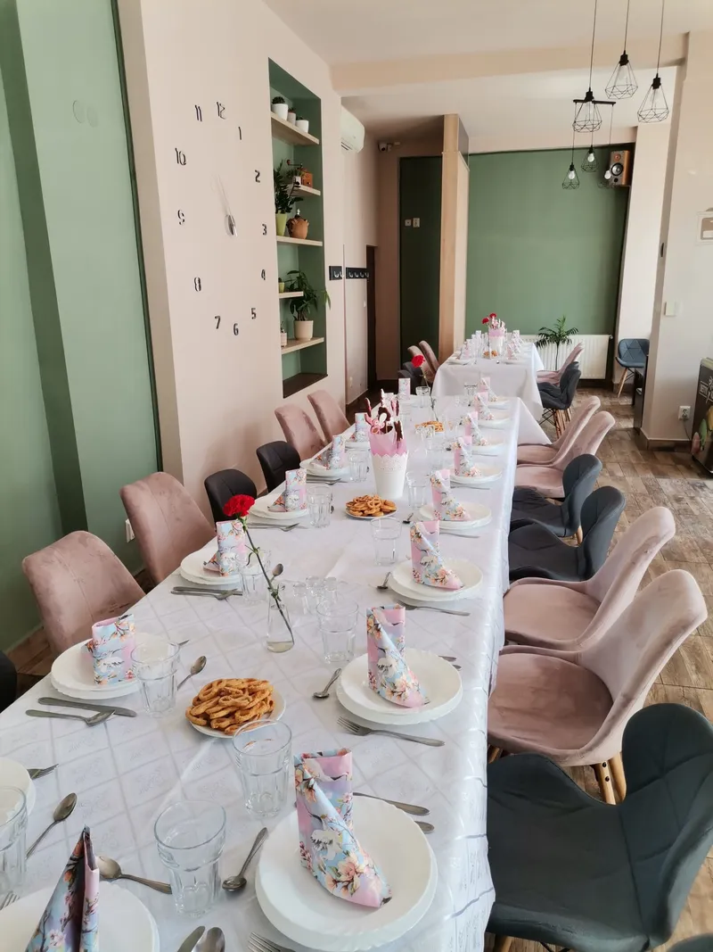 Sala de mese cu o masă lungă aranjată în alb pentru un grup
